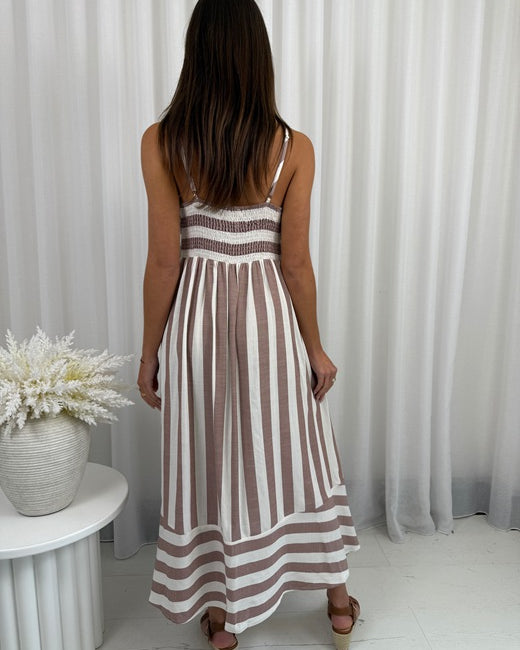 Woman wearing a striped dress standing in front of white curtains