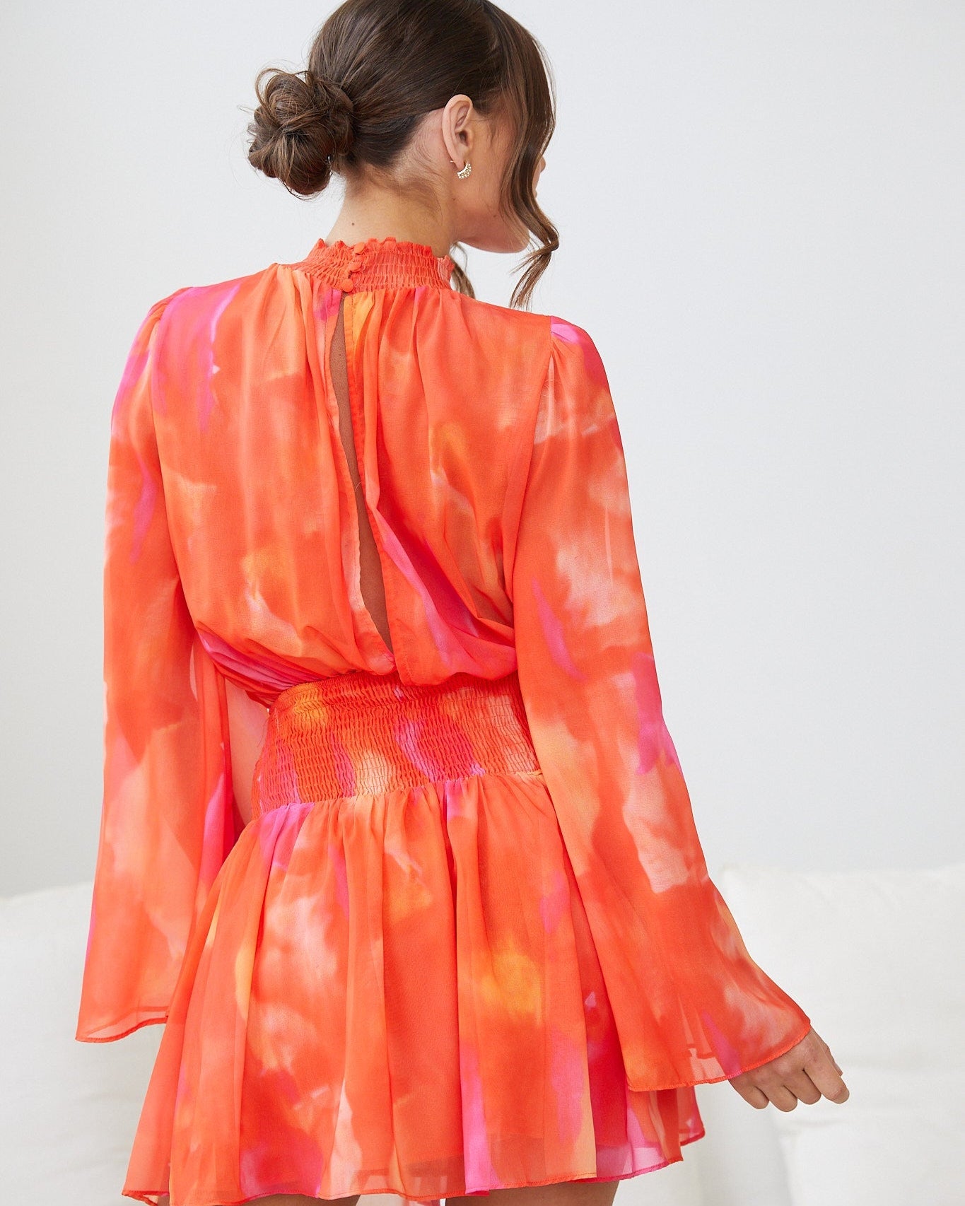 Front view of the Daenerys Mini Dress in Orange Print showing the smocked bodice and high neck detail