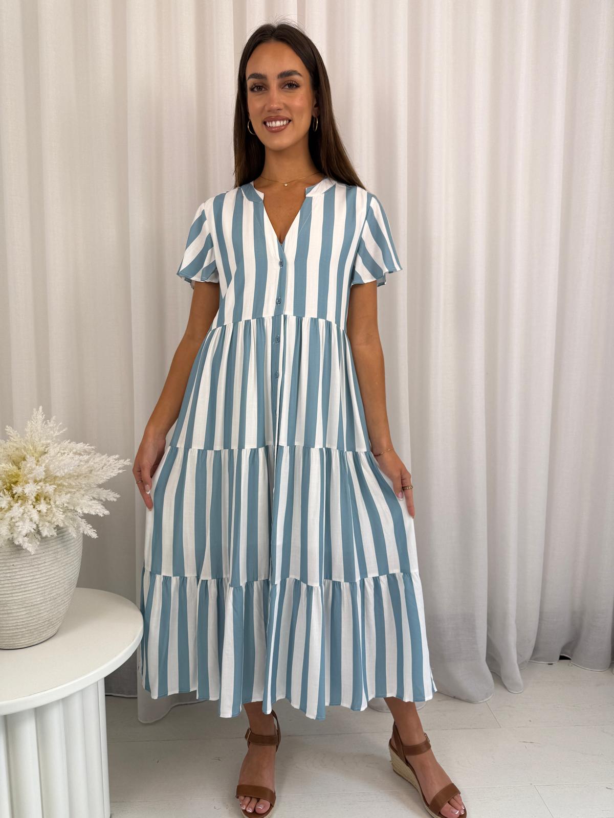 Woman wearing a blue and white striped dress against a neutral background