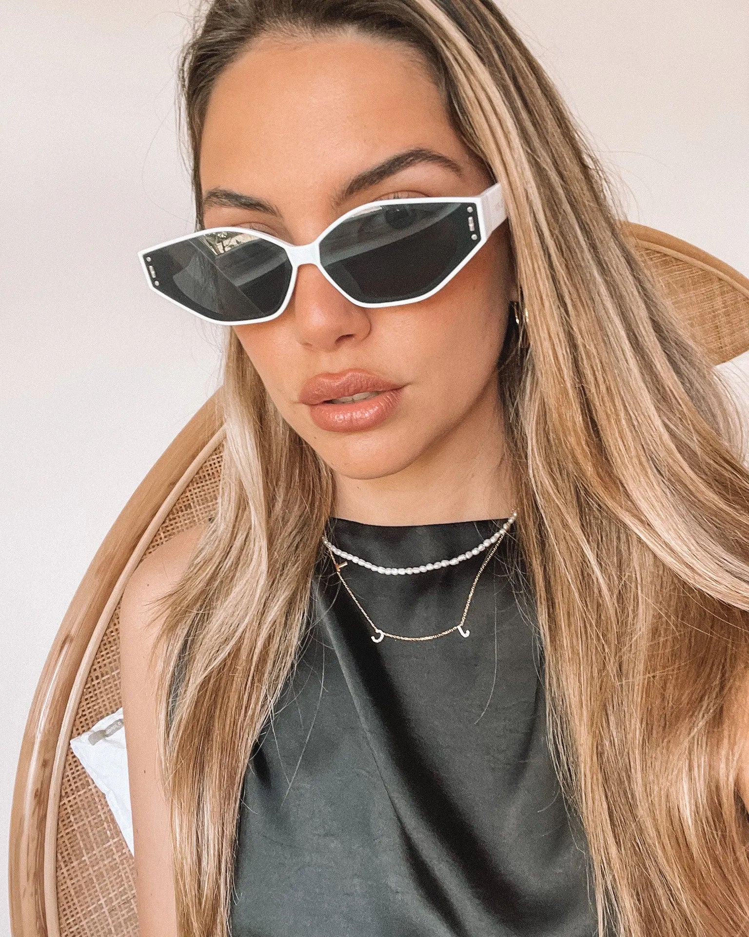 White geometric-shaped sunglasses with dark lenses resting on a light marble surface against a plain white background.