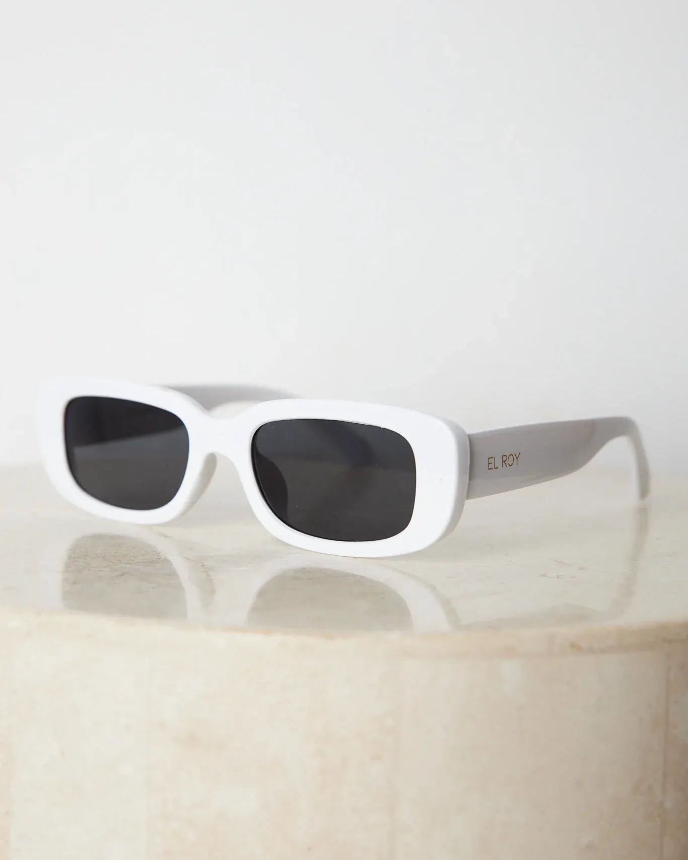 A pair of white-framed sunglasses displayed against a neutral background.