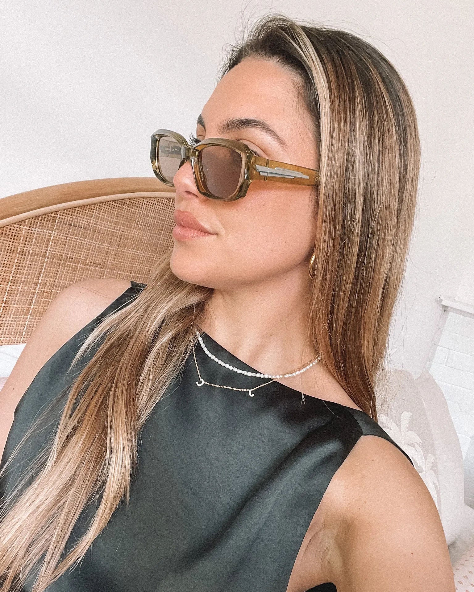 Rectangular sunglasses with translucent olive green frames and brown tinted lenses, displayed on a light beige stone surface against a plain white background.