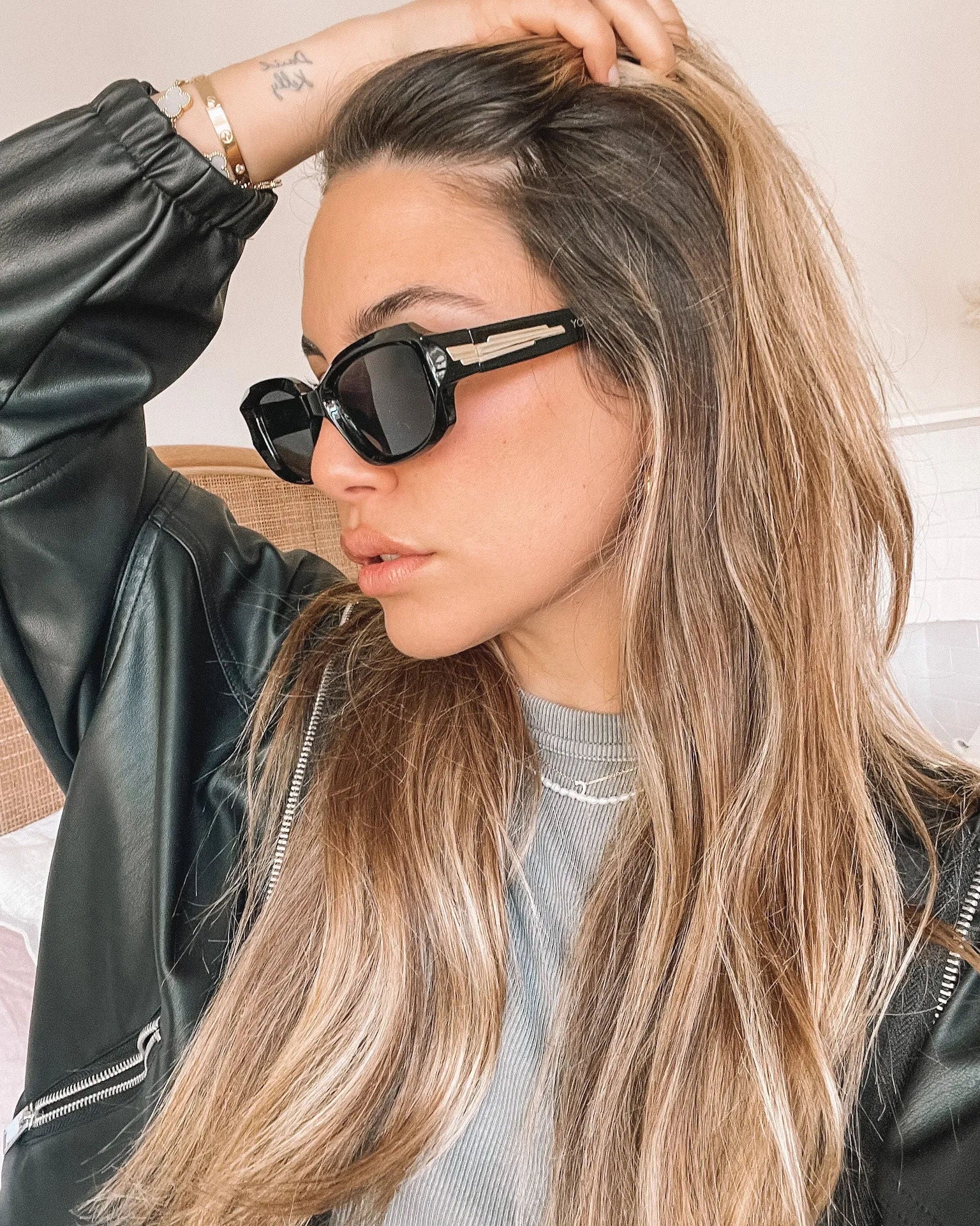 Black rectangular sunglasses with a glossy frame and dark tinted lenses, displayed on a light beige curved surface against a plain white background.