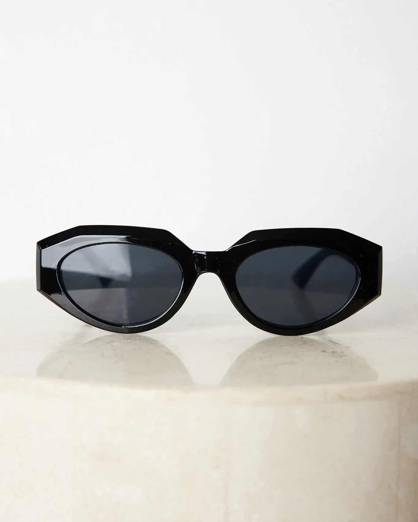 A pair of black sunglasses displayed against a neutral background.