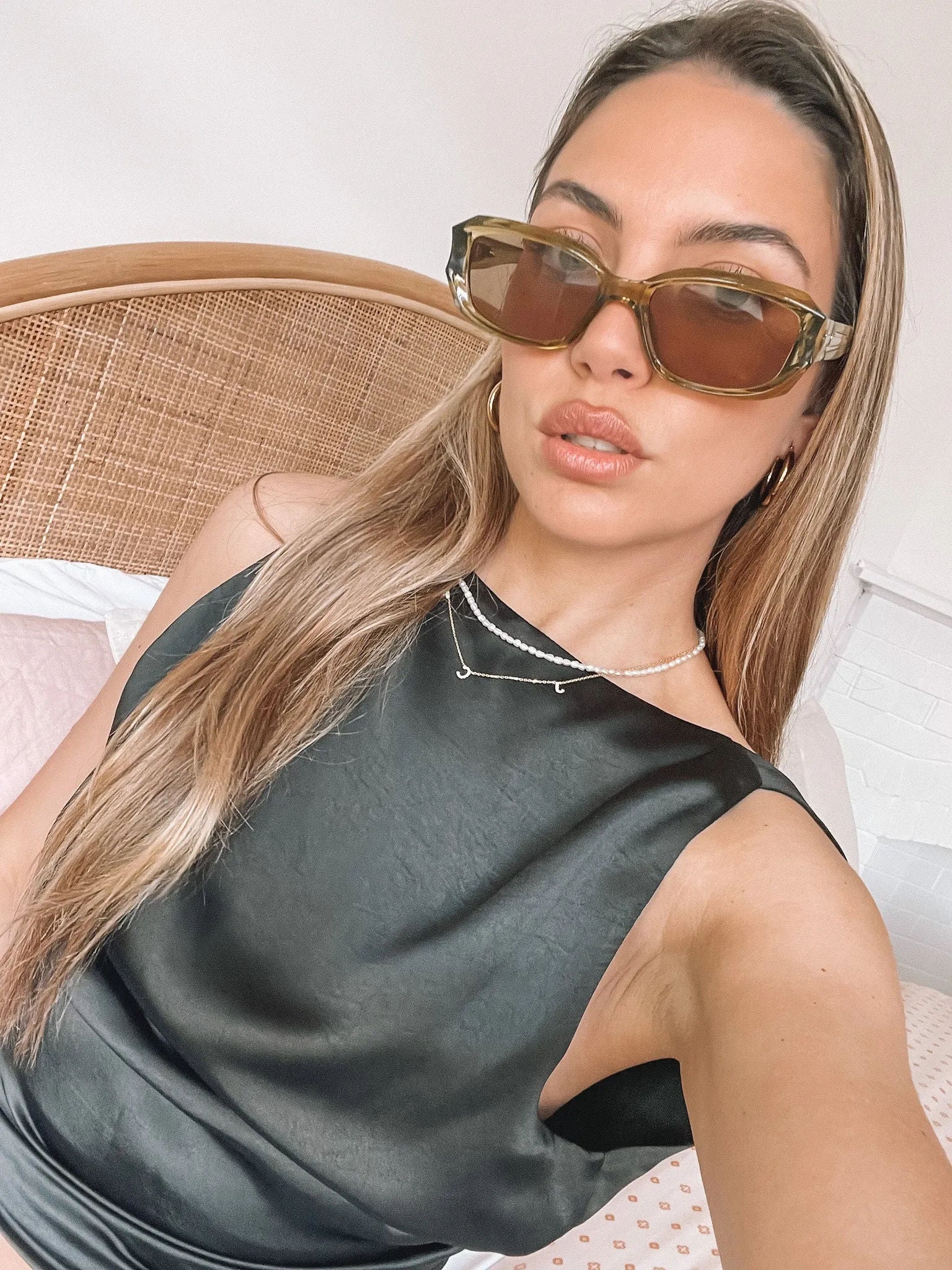 Rectangular sunglasses with translucent olive green frames and brown tinted lenses, displayed on a light beige stone surface against a plain white background.