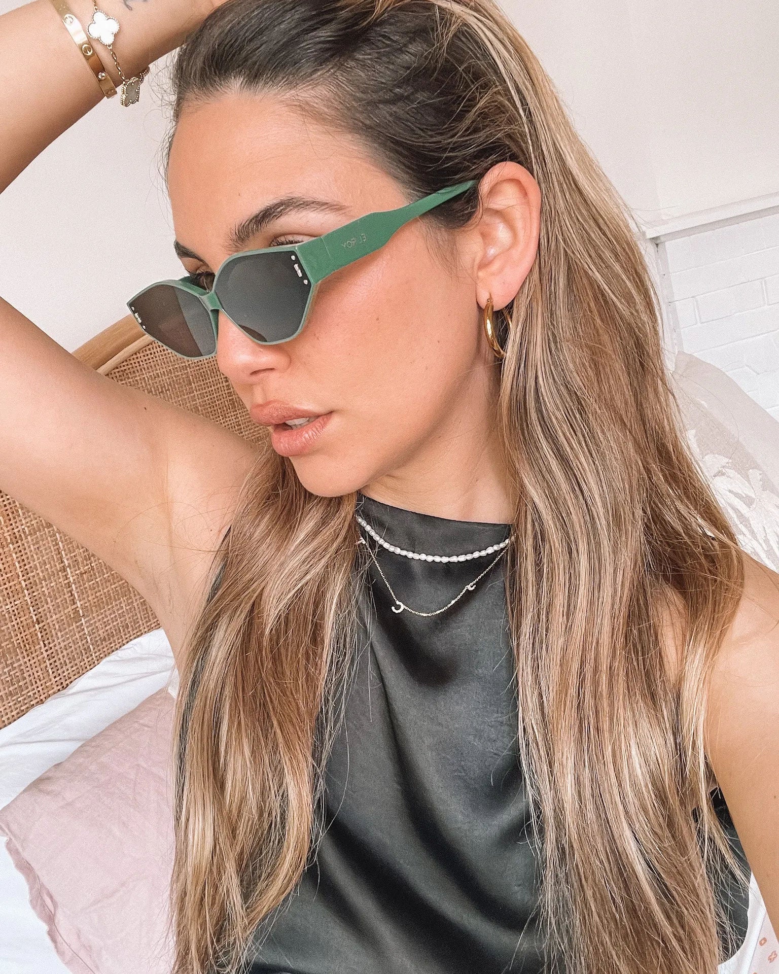 Green geometric-shaped sunglasses with dark lenses resting on a light marble surface against a plain white background.