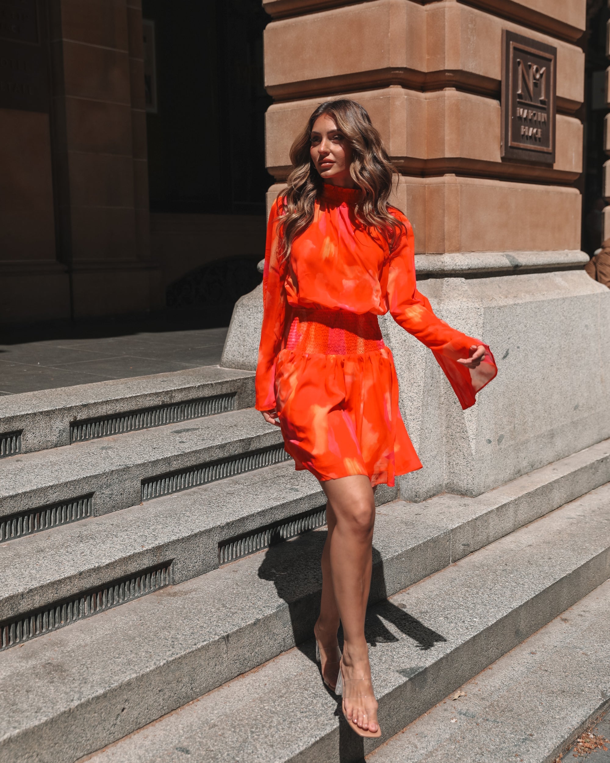 Full length view of model wearing the Daenerys Orange Print Mini Dress styled with strappy heels