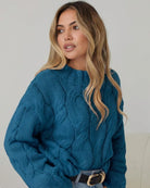 Women wearing the Hadi Knit in Teal, a cosy acrylic women's jumper in striking teal with high round neckline