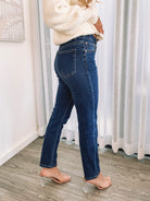 A person wearing a dark blue high-waisted, skinny fit pair of jeans with side pockets and a button and quarter zip closure.