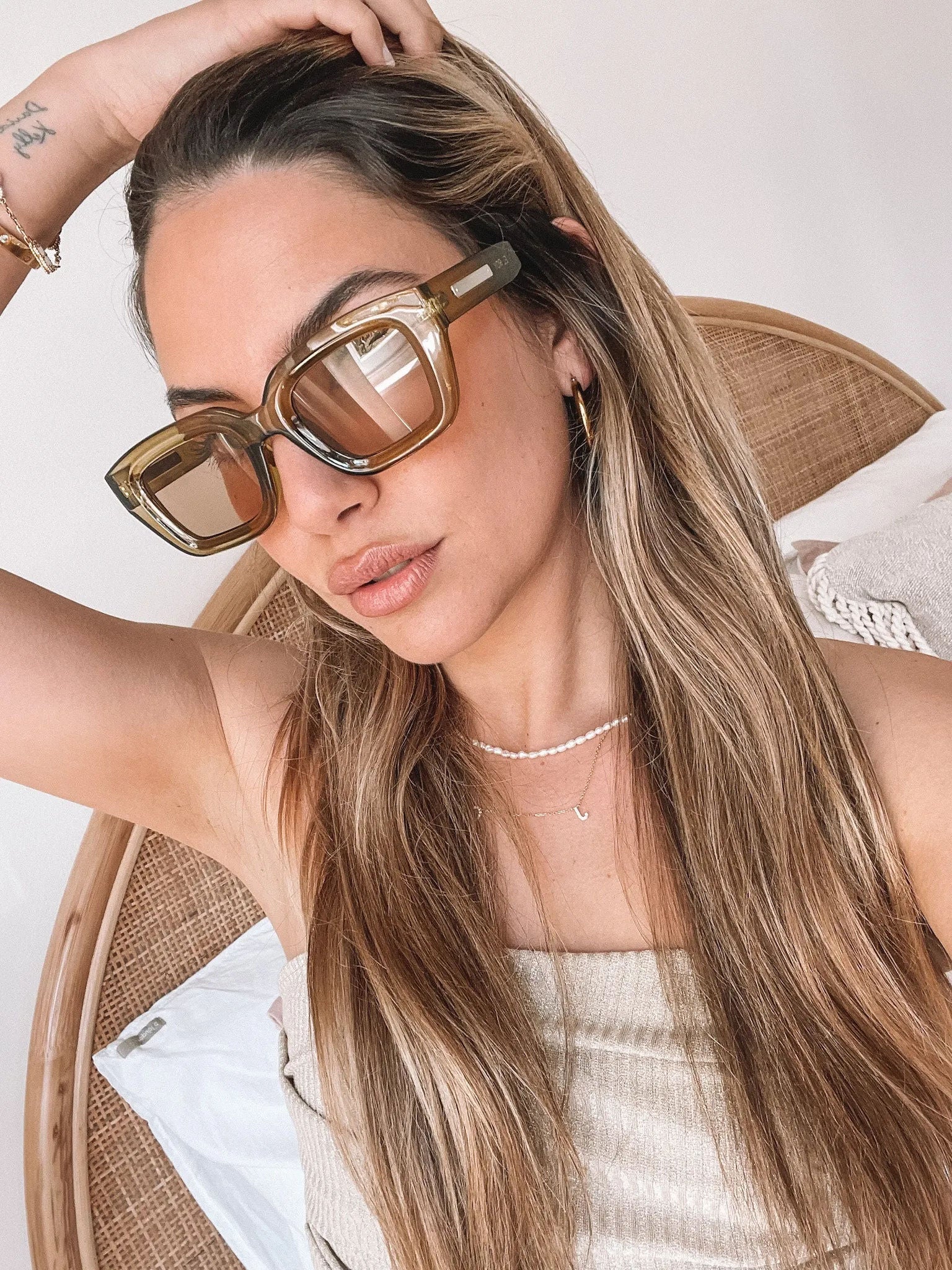 A pair of sunglasses with olive green frames and pink lenses displayed on a surface.