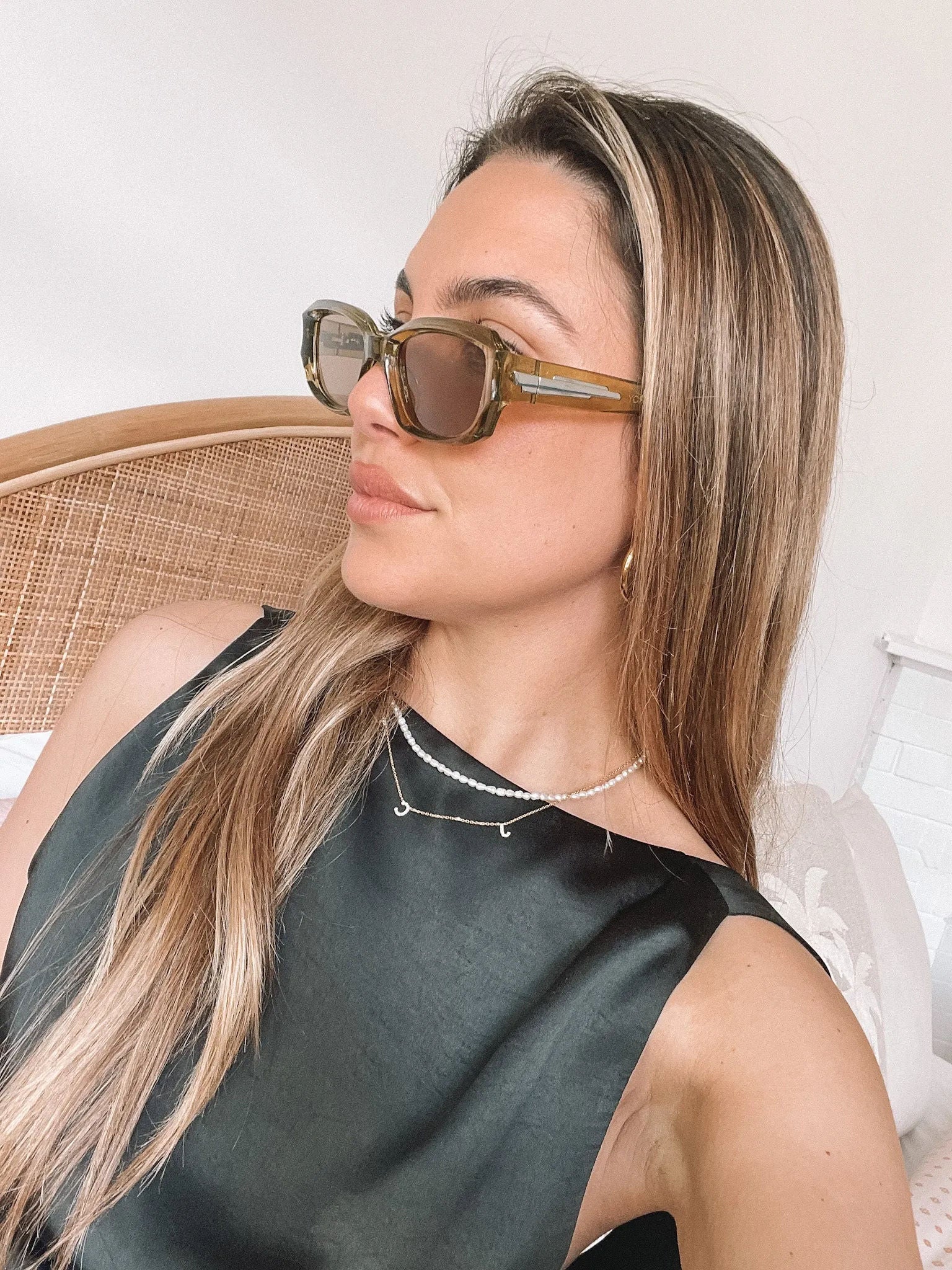 Rectangular sunglasses with translucent olive green frames and brown tinted lenses, displayed on a light beige stone surface against a plain white background.