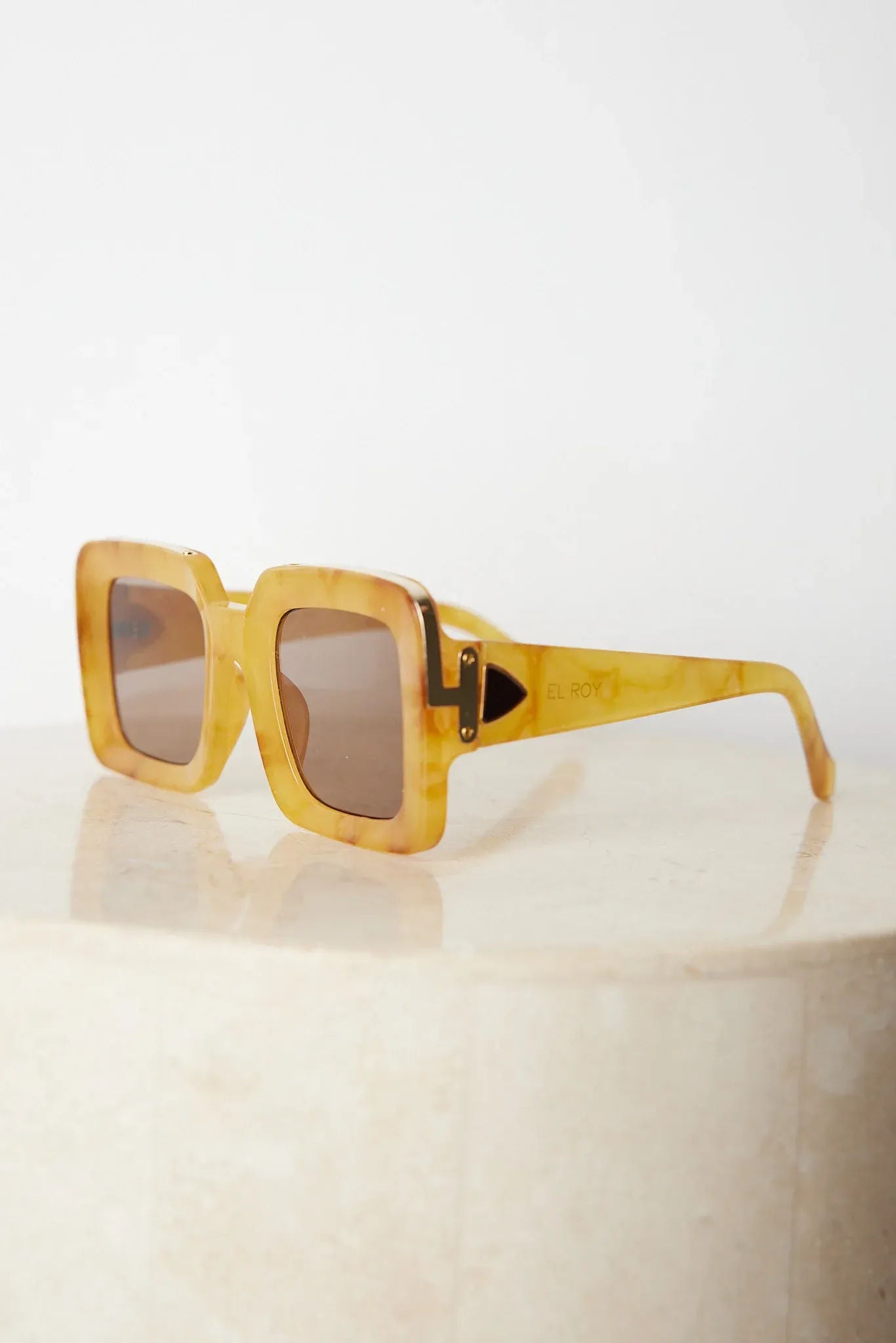 A pair of sunglasses with a tan frame displayed on a surface.